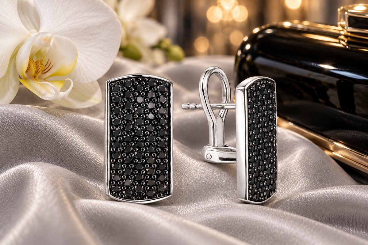 Серебряные серьги-пластины, сплошь усыпанные мелкой чёрной шпинелью, на серебристом шёлке рядом с белой орхидеей и чёрным вечерним клатчем
